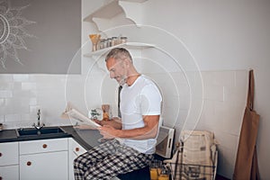 Grey-haired tall man reading a newspapaer and looking interested photo