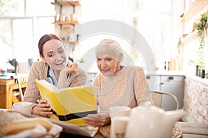 Grey-haired woman reading sitting near caregiver