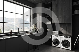 Grey interior of laundry room with washing machine and iron table, window