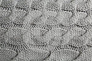 Grey knitted fabric with beautiful pattern as background, top view