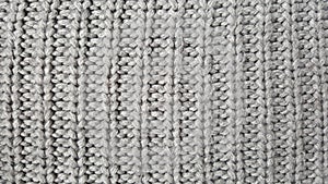 Grey knitten woolen backround. The atmosphere f a warm sweater. Texture of the wool or acrylic knit.