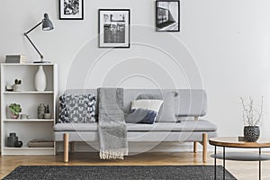 Grey lamp on white bookshelf with vases and books next to elegant settee