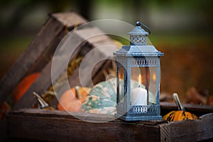 Grey lantern with burning candle on wooden box decorated in autumnal style,   in rustic style. Concept of autumn. Copy space