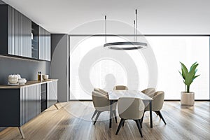 Grey living room with commode and table with beige chairs near window