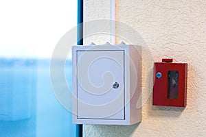Grey metal box with electrical automatics with and fire alarm and extinguisher equipment in locked key box on wall
