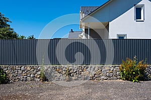 Grey metal corrugated fence in front of a residential building. Texture of profiled metal.