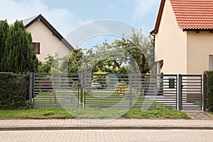 Grey metal gates near private houses on street