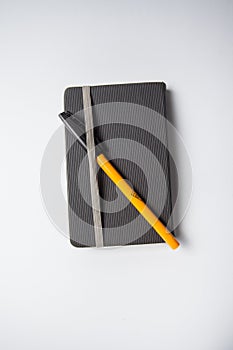 Grey notebook with a orange ballpen on it