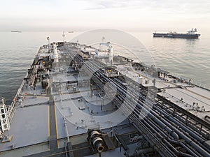 Grey oil tanker at anchor while sunset.