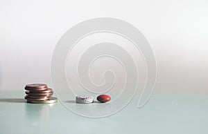 Grey and Orange drug medicine pills closeup with coin on light background with copyspace