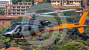 A grey and orange helicopter is flying over a city