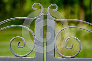 Grey painted forged metal gate. closeup