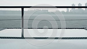 Grey pier on rainy cloudy day. River waters flowing under storm. Blurred city at the background. Nature, weather