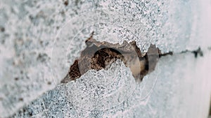 Grey plaster facade house wall with dark cracks. Close-up of cracked concrete wall