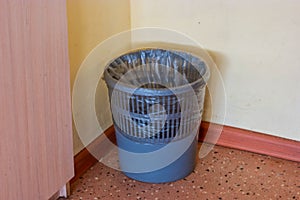 Grey plastic bin with the black clear plastic bag inside for use in the office corner