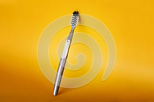 Grey Plastic Toothbrush on yellow background. Dental and healthcare concept