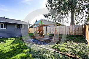 Grey rambler with kids playground in the back yard.