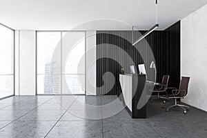 Grey reception room desk with computers near window on marble floor