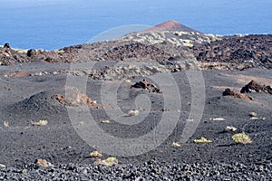 Grey-red volcano scenery in front of the blue ocean