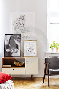 Grey retro armchair next to withe wooden cabinet