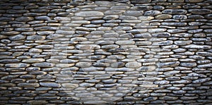 Grey river pebbles round stone wall background
