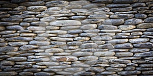 Grey river pebbles round stone wall background