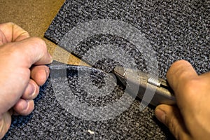 Grey roll of carpet and a knife for slicing