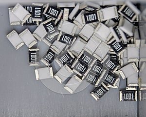 Grey scattered microscopic SMT surface mount chip resistors sorted in grey storage container