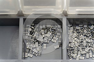 Grey scattered microscopic SMT surface mount chip resistors sorted in grey storage container photo