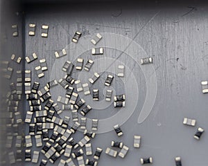 Grey scattered microscopic SMT surface mount chip resistors sorted in grey storage container photo