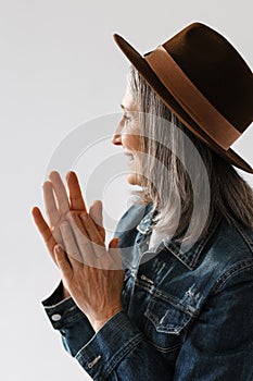 Grey senior woman in hat smiling and looking aside