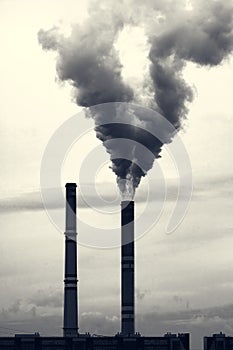 Grey smoking industrial two chimneys