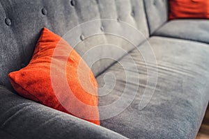Grey sofa in living room with red pillow.