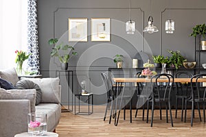 Grey sofa near black chairs at table under lamps in open space i