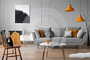 Grey sofa with pillows in elegant living room with scandinavian design