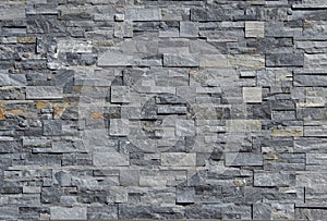 Grey stone wall cladding made of strips and square blocks stacked . Background and texture.