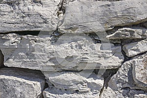 Grey stones of different shape and size in wall, background