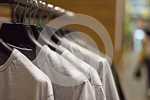 Grey t-shirts on hangers at clothing store , close up view