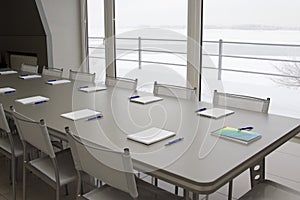 A grey table with grey chairs and notebooks laying