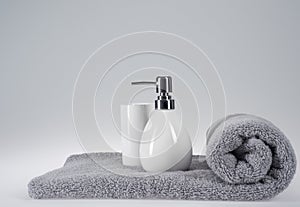 Grey terry towel with liquid soap dispenser on a light background
