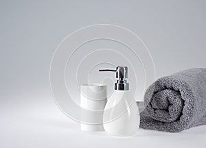 Grey terry towel with liquid soap dispenser on a light background