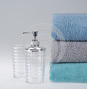 Grey terry towel with liquid soap dispenser on a light background