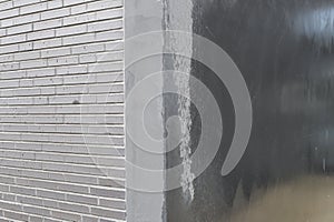 Grey textured concrete background with brick wall