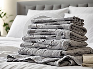 Grey towels lies on clean white bed. Cleaning in guest room of hotel, cleanliness