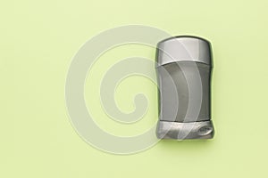 A grey tube with deodorant on a green background