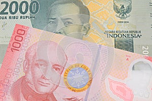 A grey two thousand Indonesian rupiah bank note paired with a colorful red one thousand colones bank note from Costa Rica.