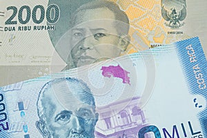 A grey two thousand Indonesian rupiah bank note paired with a colorful two thousand colones bank note from Costa Rica.
