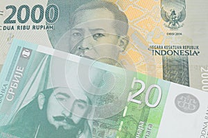 A grey two thousand Indonesian rupiah bank note paired with a green and white twenty dinar banknote from Serbia.