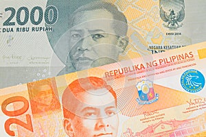 A grey two thousand Indonesian rupiah bank note paired with a orange and white twenty piso note from the Phillipines.