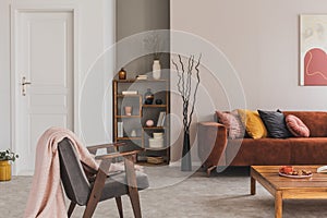 Grey vintage armchair with pastel pink blanket in elegant and atmospheric apartment